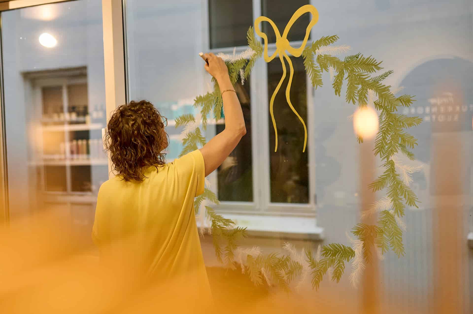 Mette Poulsen maler håndmalet julemotiv på butiksrude
